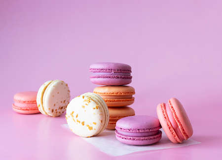 Pink, lilac, beige macaroons on white parchment. Light lilac background