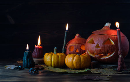 Small orange pumpkins on a wooden table. Candles in the form of panicles burn in the background. Black spiders on the table. dark wooden backgroundの写真素材
