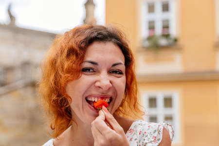 Portrait of the beautiful young woman with fresh red strawberries. Girl enjoy eating appetizing and juicy strawberry. Healthy foodの写真素材