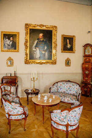 Castle interior. Tea room. A table with a tea set, an antique grandfather clock and paintings on the...