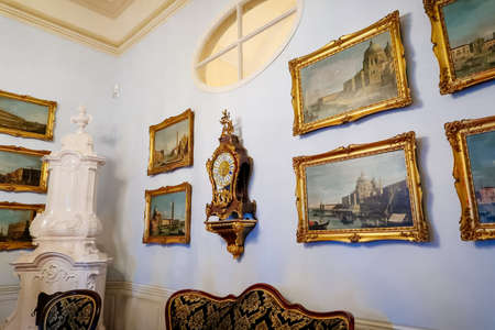 Castle interior. Antique clock and paintings in carved frames on the wall. Renaissance castle...