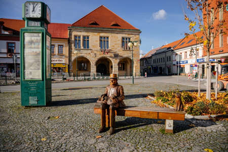 Wooden sculpture of Czech writer Bohumil Hrabal, bench with a cat, Premyslid Square and Hlav's house in sunny autumn day, Nymburk, Central Bohemia, Czech Republic, November 17, 2020のeditorial素材