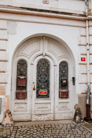 Elements of architectural decoration of buildings, old ancient wooden white door on around arch with stone wall, graceful forged lattice, Cesky Brod, Czech Republic, November 28, 2020のeditorial素材