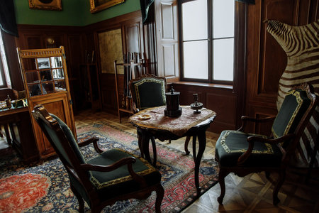 Horovice castle interior, Baroque chateau, carved wooden furniture in green hunting salon with trophies, writing desk, rifles on stands, Czech Republic, October 08, 2017のeditorial素材
