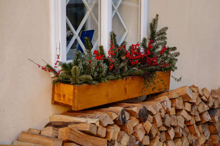 Window decoration for Christmas in the form of plant branches and red berries in a wooden pot on the...