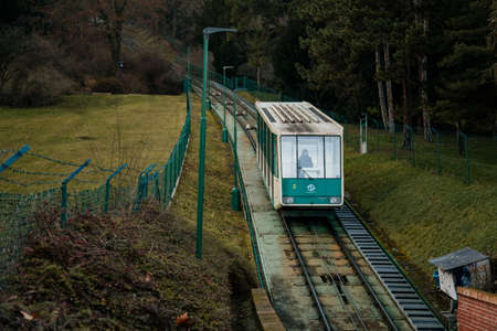 Green funicular car from Ujezd to Petrin hill as a part of public transportation, park garden, benches, trees and shades on sunny winter day, Prague, Czech Republic, January 25, 2021のeditorial素材