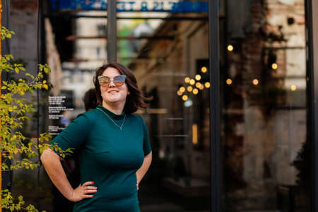 Portrait of stylish young pretty hipster woman in sunglasses and green dress, vintage urban...