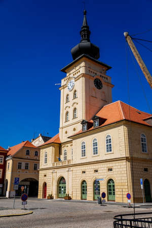 Yellow classic town hall with clock tower at main Freedom square, renaissance and baroque historical buildings, blue sky, Medieval street, sunny day, Zatec, Bohemia, Czech Republic, April 04, 2021のeditorial素材