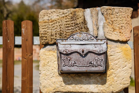 Vintage wrought iron mailbox for correspondence and letters weighs on a stone fence, Brown white metallic Antique Letter Box on wall, chipped and peeling paint, blurred background, selective focusの写真素材
