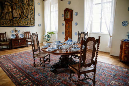 Castle interior, renaissance furniture, round table and carved chairs, white-blue porcelain service,...