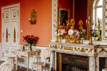 Velke Brezno, Czech Republic, 26 June 2021: chateau Velke Brezno, castle interior, baroque furniture, red dining room with open fireplace and large mirror, gold plated antique clock on mantel.のeditorial素材