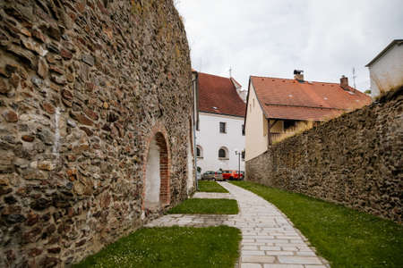 Pelhrimov, Czech Republic, 03 July 2021: narrow picturesque street with stone ancient fortress walls at summer day in center of town, gothic church of St. Bartholomew with observation tower.のeditorial素材