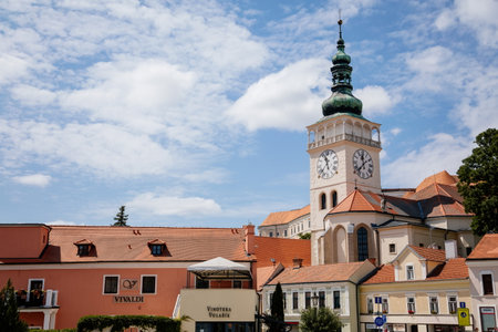 Mikulov, South Moravian Region, Czech Republic, 05 July 2021: medieval church square and white observation clock tower of St. Wenceslas church, green dome and red tile roofs at sunny summer day.のeditorial素材