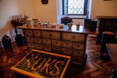 Kuks, East Bohemia, Czech Republic, 10 July 2021: Baroque hospital Kuks, interior of historic pharmacy, Vintage glass bottles on wooden table and shelf, medical background, Museum antique drugstore.のeditorial素材