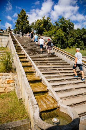 Kuks, East Bohemia, Czech Republic, 10 July 2021: well or a fountain with statues of Triton Greek god of sea, staircase with water cascade at sunny summer day, baroque castle and hospital Kuksのeditorial素材