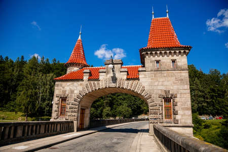 Bila Tremesna, Czech Republic, 10 July 2021: Amazing colorful view of Les Kralovstvi historic hydraulic water dam with orange water in river Elbe, Kingdom Forest, road with towers at sunny summer day.のeditorial素材