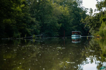 South Moravia, Czech Republic: Landscape by the water. Stara or old Dyje river near Januv hrad at Lednice Valtice areal in sunny summer day, Calm water and green trees, Cruise ship in castle park.のeditorial素材