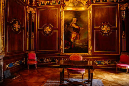 Valtice, Southern Moravia, Czech Republic, 04 July 2021: romantic castle interior with baroque furniture, wooden carved writing desk and chair on the carpet, wood wall panels with gilding, chateau.のeditorial素材