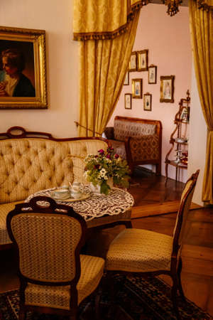 Jaromerice nad Rokytnou, Czech Republic, 06 July 2021: Castle interior with baroque wooden carved furniture, sofa and soft armchairs, porcelain tea set on table, paintings in gilded frames.のeditorial素材