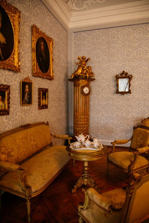 Jaromerice nad Rokytnou, Czech Republic, 06 July 2021: Castle interior with baroque wooden carved furniture, sofa and soft armchairs, porcelain tea set on table, paintings in gilded frames.のeditorial素材