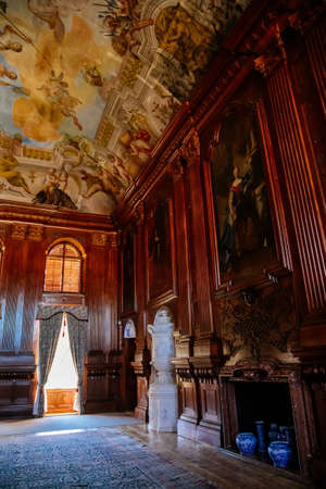 Jaromerice nad Rokytnou, Czech Republic, 06 July 2021: Castle interior with baroque wooden carved furniture, grand hall with wood panels, paintings on the walls, painted ceiling with colored frescoes.のeditorial素材