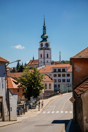 Trebic, Bohemia, Czech Republic, 06 July 2021: Narrow picturesque street with colorful buildings in historic center, renaissance and baroque medieval city, Church of St. Martina at sunny summer day.のeditorial素材