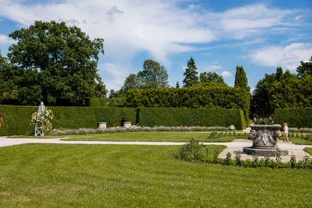 Lednice, Southern Moravia, Czech Republic, 04 July 2021: chateau with beautiful gardens, green parks at sunny summer day, neo-gothic romantic castle, geometric flower bed, roses and stone vase.のeditorial素材