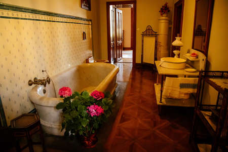 Lednice, Southern Moravia, Czech Republic, 04 July 2021: Castle interior with baroque wooden carved furniture, antique bathroom with large ceramic bathtub and toilet, painted tiles, romantic chateau.のeditorial素材