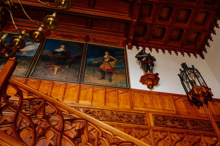 Lednice, Southern Moravia, Czech Republic, 04 July 2021: Castle interior with neo-gothic wooden carved furniture, Decorative staircase at hall, floral ornaments, chandelier candelabrum with candles.のeditorial素材