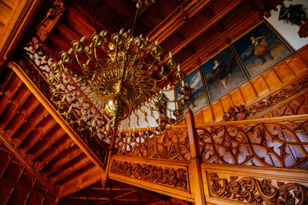 Lednice, Southern Moravia, Czech Republic, 04 July 2021: Castle interior with neo-gothic wooden carved furniture, Decorative staircase at hall, floral ornaments, chandelier candelabrum with candles.のeditorial素材