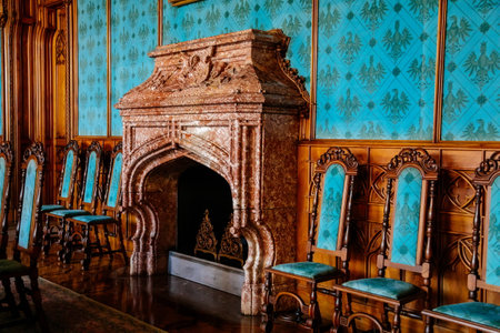 Lednice, Southern Moravia, Czech Republic, 04 July 2021: Castle interior with neo-gothic wooden carved ceiling and furniture, blue salon with chairs, open marble fireplace.のeditorial素材
