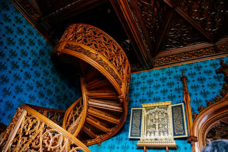 Lednice, Southern Moravia, Czech Republic, 04 July 2021: Castle interior with neo-gothic romantic wooden carved furniture, Decorative spiral staircase with floral ornaments at blue chateau library.のeditorial素材