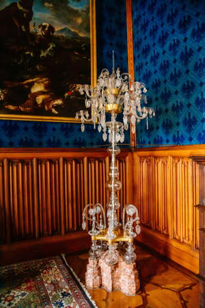 Lednice, Southern Moravia, Czech Republic, 04 July 2021: Castle interior with neo-gothic wooden carved ceiling and furniture, tall crystal floor chandelier, venetian glass chandelier, antique lamp.のeditorial素材