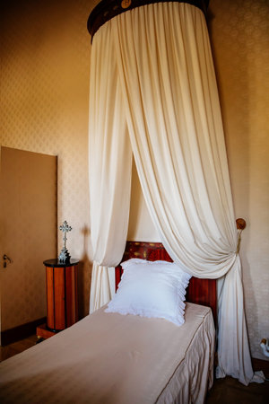 Lednice, Southern Moravia, Czech Republic, 04 July 2021: Castle interior with baroque wooden carved furniture, bedroom with canopy bed, crucifix on the bedside table, beautiful UNESCO chateau.のeditorial素材