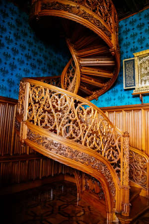 Lednice, Southern Moravia, Czech Republic, 04 July 2021: Castle interior with neo-gothic romantic wooden carved furniture, Decorative spiral staircase with floral ornaments at blue chateau library.のeditorial素材