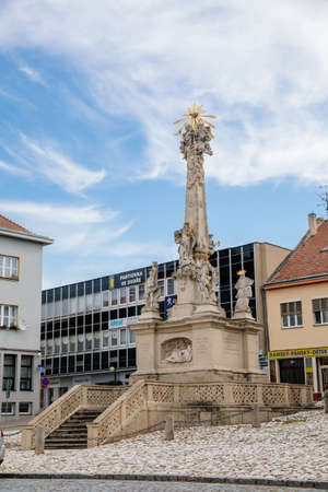 Hustopece, Southern Moravia, Czech Republic, 04 July 2021: baroque Holy Trinity Column with stone statues of saints at main square at sunny summer day in historic center.のeditorial素材