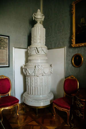 Vranov nad dyji, Southern Moravia, Czech Republic, 03 July 2021: Castle interior with baroque wooden carved furniture, white ceramic tiled stove, chairs and paintings in gilded frames.のeditorial素材