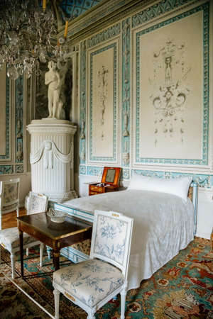 Vranov nad dyji, Southern Moravia, Czech Republic, 03 July 2021: Castle interior, baroque wooden carved furniture, blue and white bedroom, painted walls with floral ornament, bed and chairs, statues.のeditorial素材