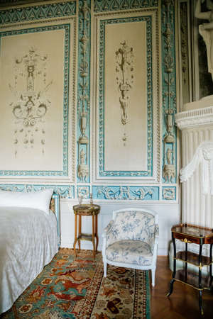 Vranov nad dyji, Southern Moravia, Czech Republic, 03 July 2021: Castle interior, baroque wooden carved furniture, blue and white bedroom, painted walls with floral ornament, bed and chairs, statues.のeditorial素材