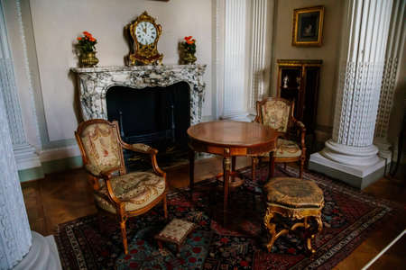 Vranov nad dyji, Southern Moravia, Czech Republic, 03 July 2021: Castle interior, baroque wooden carved furniture, table and chairs, open marble fireplace, painted walls and columns, floral ornament.のeditorial素材
