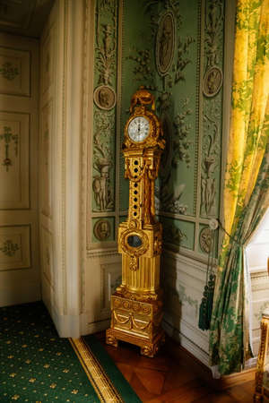 Vranov nad dyji, Southern Moravia, Czech Republic, 03 July 2021: Castle interior, baroque wooden carved furniture, green guest salon, painted walls with floral ornament, gold plated grandfather clock.のeditorial素材