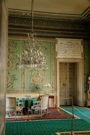 Vranov nad dyji, Southern Moravia, Czech Republic, 03 July 2021: Castle interior, baroque wooden carved furniture, green guest salon, painted walls, porcelain service on table, crystal chandelier.のeditorial素材