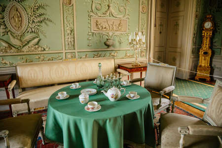 Vranov nad dyji, Southern Moravia, Czech Republic, 03 July 2021: Castle interior, baroque wooden carved furniture, green guest salon, painted walls, porcelain service on table, crystal chandelier.のeditorial素材