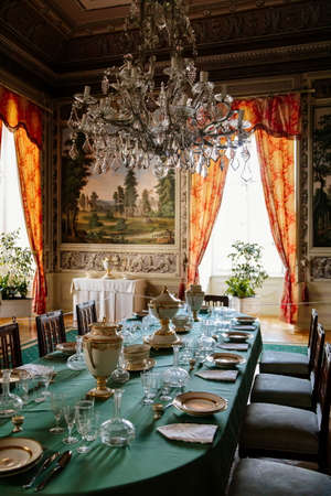 Vranov nad dyji, Southern Moravia, Czech Republic, 03 July 2021: Castle interior with baroque wooden carved furniture, dining room with painted walls, porcelain service and crystal glasses on table.のeditorial素材