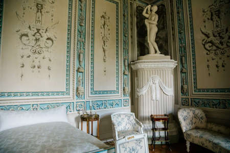 Vranov nad dyji, Southern Moravia, Czech Republic, 03 July 2021: Castle interior, baroque wooden carved furniture, blue and white bedroom, painted walls with floral ornament, bed and chairs, statues.のeditorial素材