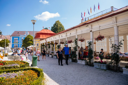 Lazne Libverda, North Bohemia, Czech Republic, 04 September 2021: red and white colonnade at sunny summer day, historical spa, city fair selling food and souvenirs, flowers and roses in baskets.のeditorial素材