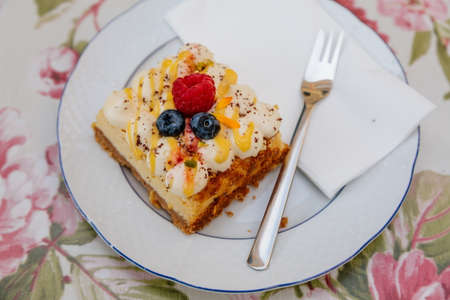 Mille-feuille or milhoja, Portion cake, Puff pastry with vanilla butter cream and whipped cream on white plate with dessert fork, fresh lingonberries and raspberries, selective focus, Castolovice cafeの写真素材