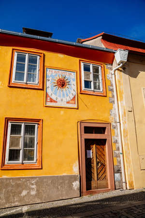 Kolin, Central Bohemia, Czech Republic, 10 July 2021: Narrow picturesque street with colorful renaissance baroque historical houses in medieval town center, sundial with the image of the sun.のeditorial素材