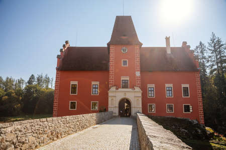 Cervena Lhota, South Bohemia, Czech Republic, 9 October 2021: Beautiful small romantic red water chateau, Antique castle with fall color at sunny autumn day, stone bridge and entrance gateのeditorial素材