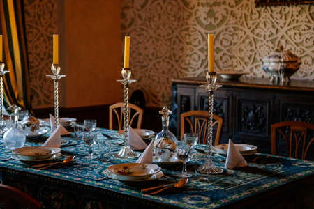Cervena Lhota, South Bohemia, Czech Republic, 9 October 2021: Castle interior, baroque wooden carved furniture, dining room with floral ornaments on walls, porcelain set on table, glass candlesticksのeditorial素材